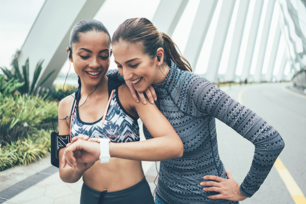 two girl friends looking at fitness watch while doing exercise